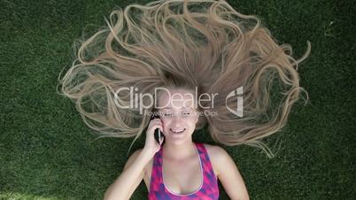 Woman with blonde amazing long hair lying on grass