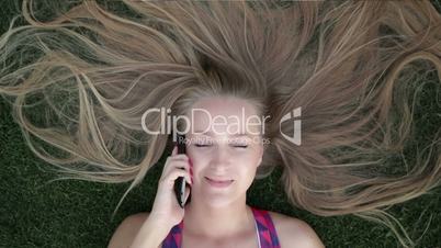 Girl with beautiful blonde hair lying on grass
