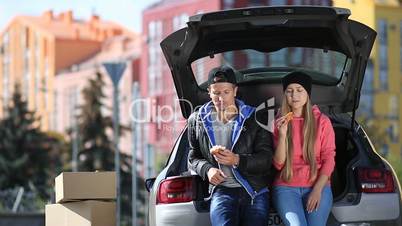 Smiling couple sitting in trunk of modern car
