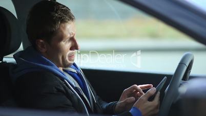 Man sits in car holding tablet with GPS navigator