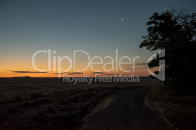 Fantastic sunrise and moon above the field.