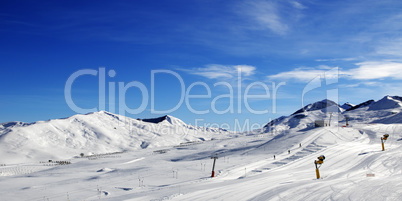 Panoramic view on ski slope with snowmaking at sun day