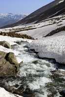 Mountain river with snow bridges in spring sun day