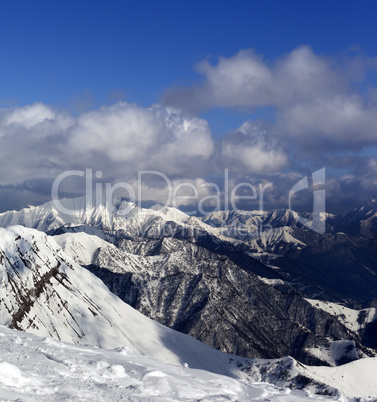 Sunlit mountains in clouds, view from off-piste slope