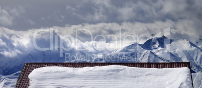 Panoramic view on snowy roof and mountains in clouds