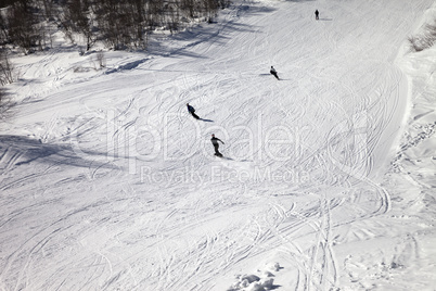 Skiers and snowboarders on ski slope at sun winter day