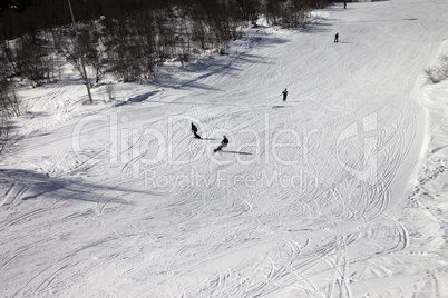 Skiers and snowboarders on ski slope at sun winter day