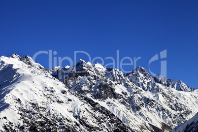 Snowy rocks and blue clear sky at cold sun day