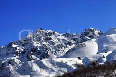 Snowy rocks and off-piste slope in sunny morning