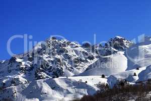 Snowy rocks and off-piste slope in sunny morning