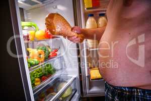 Hungry man holding a turkey leg in his hands and standing next t