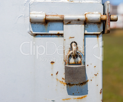 Padlock on partly rusted metal latch.