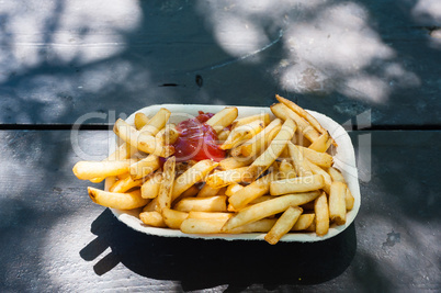 French fries with ketchup in paper tray.