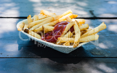 French fries with ketchup in paper tray.