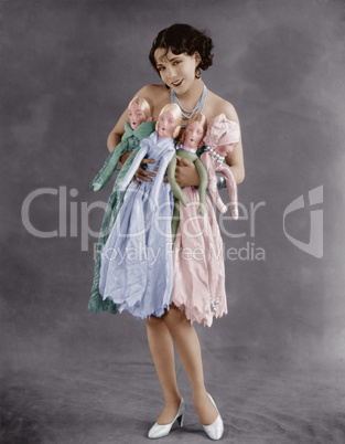 Portrait of young woman holding four dolls