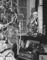 Young boy admiring Christmas tree and presents from window