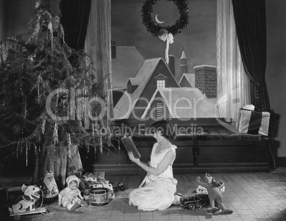 Teenage girl reading book with Christmas tree