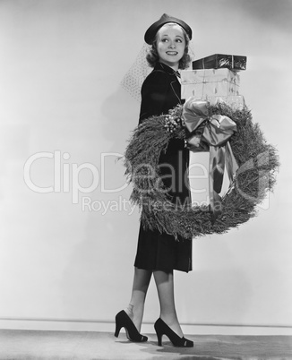 Portrait of female shopper with wreath and Christmas gifts