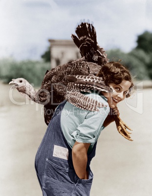 Portrait of woman with live turkey slung over shoulder