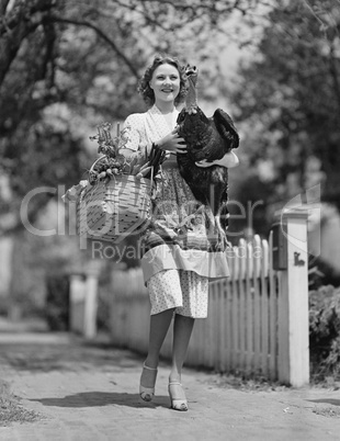 Woman carrying live turkey and grocery basket