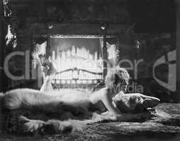 Woman relaxing on bear rug in front of fire