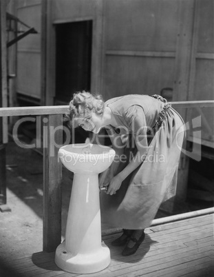 Portrait of woman drinking from water fountain