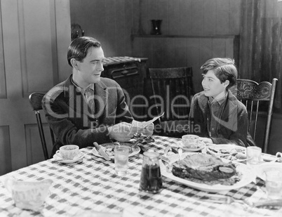 Portrait of father and son at dinner table