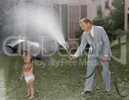 Toddler and dad playing with hose in yard