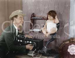 Father with baby in speaker horn of old radio