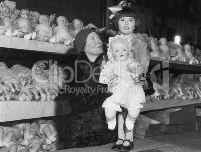 Mother and daughter with shelves of dolls