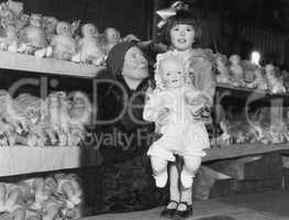 Mother and daughter with shelves of dolls