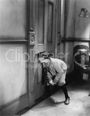 Teenage boy peeping through keyhole