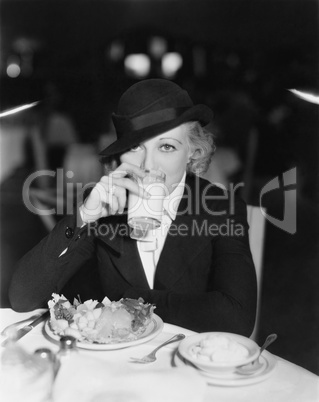 Portrait of woman drinking and eating in restaurant