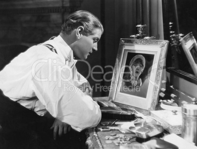 Man looking at portrait of woman