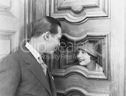 Couple interacting through hole in door