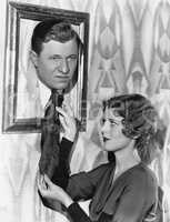 Woman adjusting tie of man in picture frame