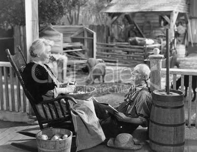 Elderly couple on porch of farmhouse