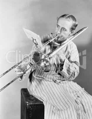 Man playing trombone in nightgown