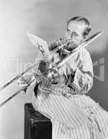 Man playing trombone in nightgown