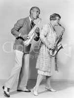 Couple playing saxophones together