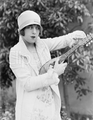 Woman tuning mandolin outside