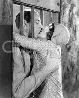 Couple kissing through bars of jail cell