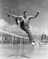 Male tennis player jumping over net