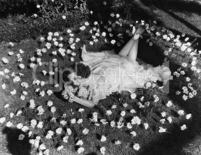 Woman lying on grass surrounded by flowers