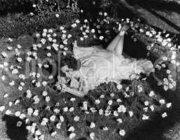 Woman lying on grass surrounded by flowers