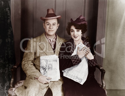 Portrait of smiling couple with newspapers