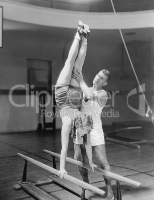 Coach helping woman on parallel bars