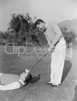 Man hitting golf ball on mans forehead