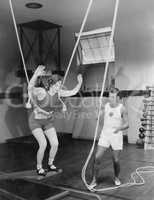 Female gymnast training with safety ropes with coach