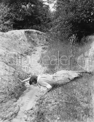 Woman drinking from tiny stream